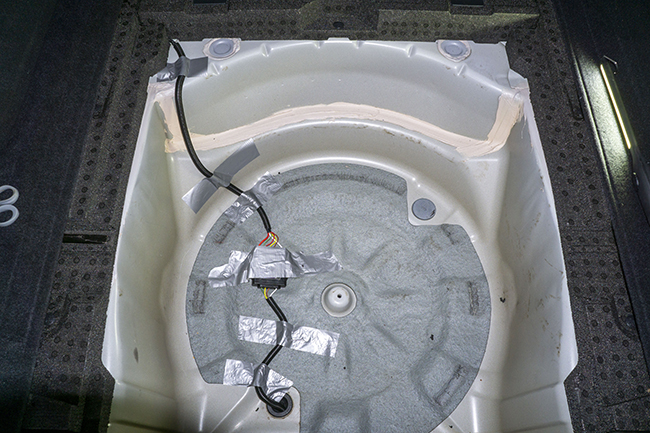 Photograph of Hopkins plug in vehicle wiring harness with 4 pole connector inside 2010 Subaru Outback spare tire well after protective conduit was installed.